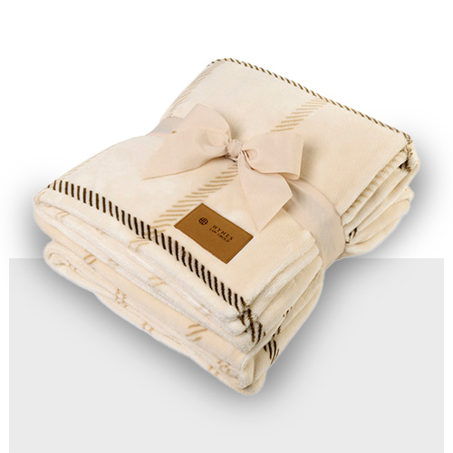 Tan and brown folded sherpa blanket with ribbon tied around it and faux leather patch on corner
